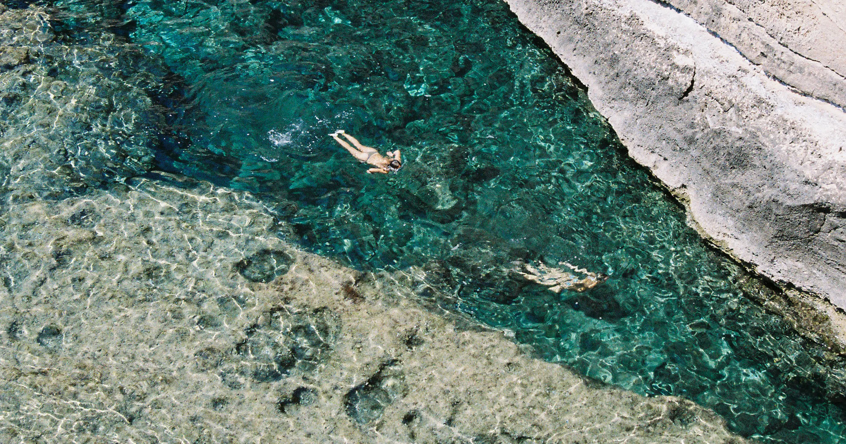 Image taken in Cala El Toro that depicts two young women swimming relaxed in turquese water.