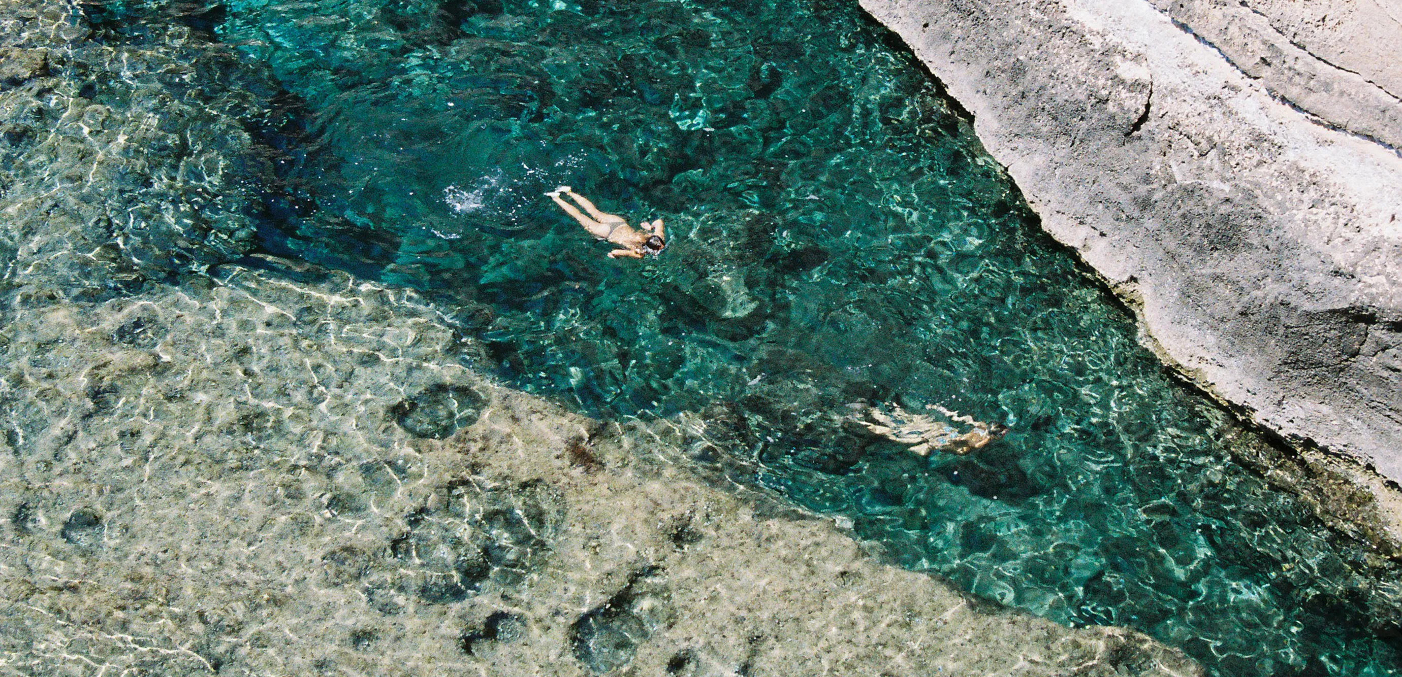Image taken in Cala El Toro that depicts two young women swimming relaxed in turquese water.