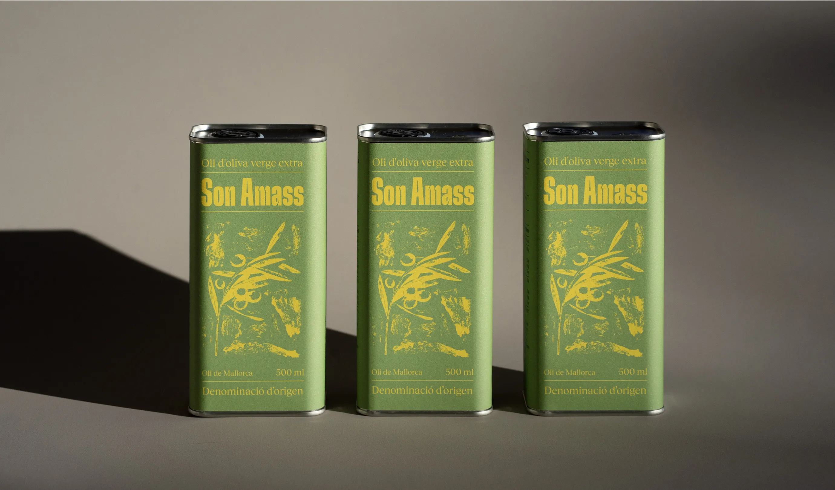Three Son Amass extra virgin olive oil cans standing to each other.
